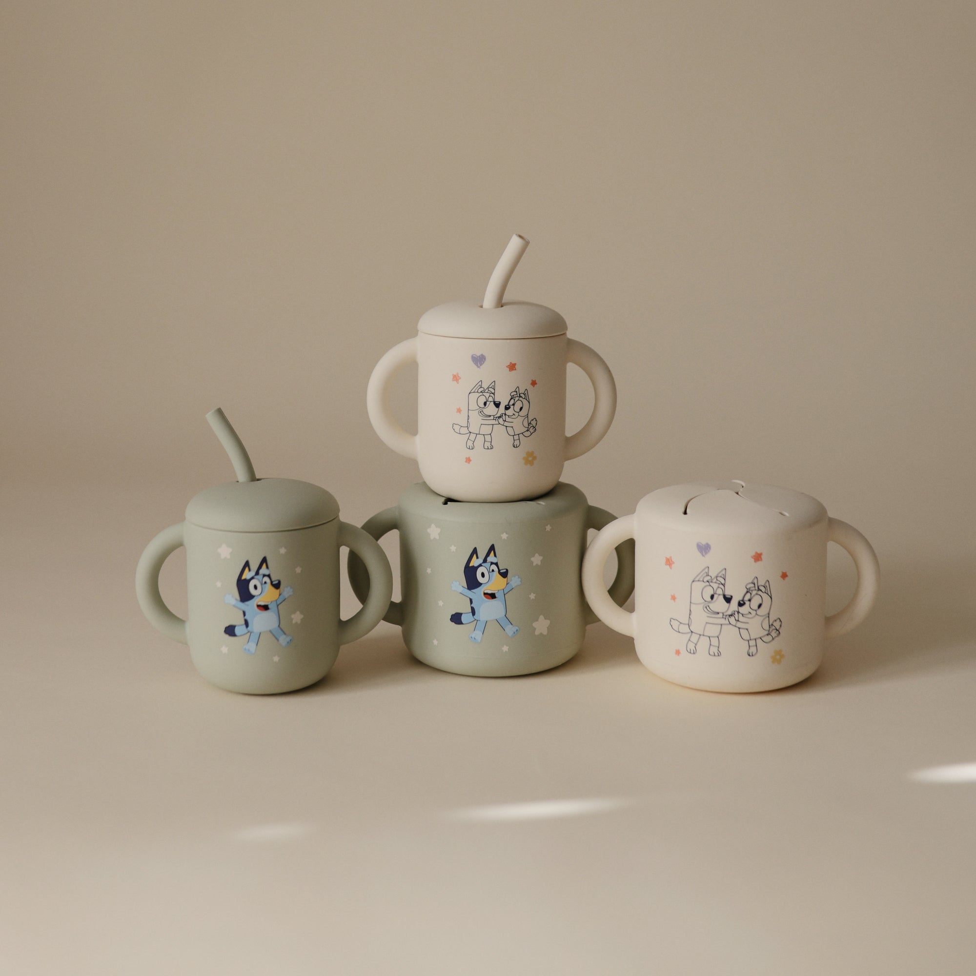Four mushie Bluey Gift Set silicone feeding cups with cartoon animal designs, stacked together.