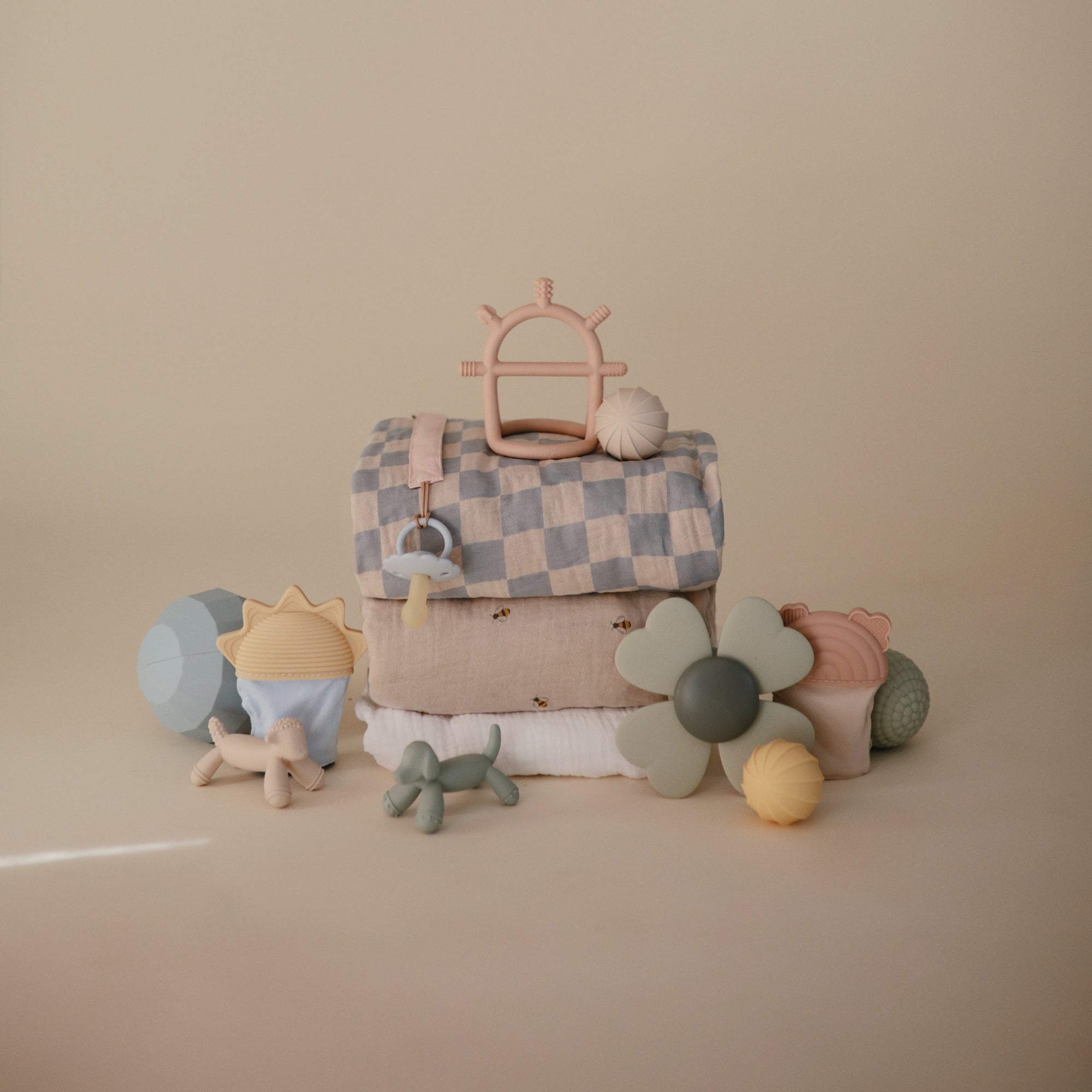 Mushie Extra Soft Muslin Crib Sheet and neutral baby toys displayed on a beige background.