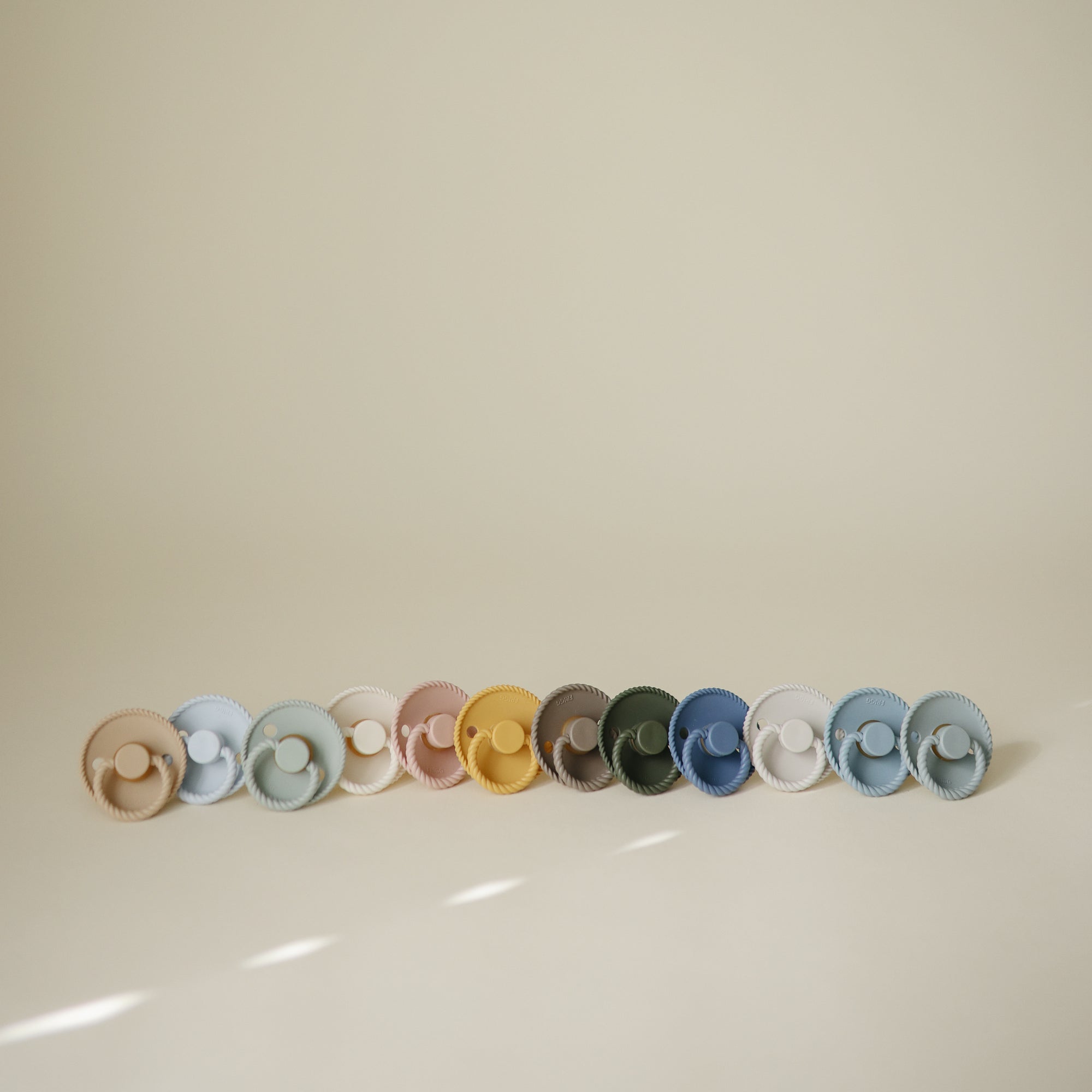 Five FRIGG Rope Natural Rubber Pacifier 2-Packs by Mushie arranged on a neutral background.