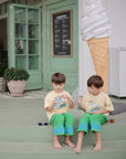 Two kids with mushie Silicone Sensory Toy fidget beside a shop's giant ice cream cone statue.