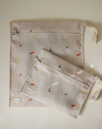 Two beige Water Resistant Wet Bag pouches with zippered closures and dinosaur illustrations.