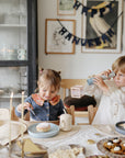 Two kids enjoy Hanukkah treats; one plays with a mushie Kaleidoscopes toy.