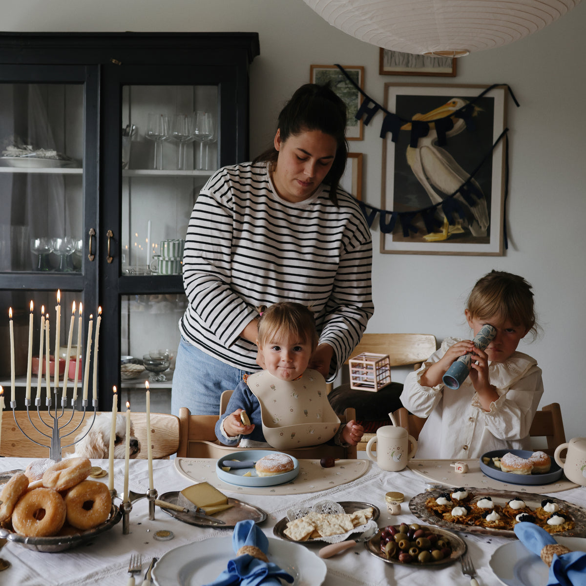 Woman and kids enjoy snacks and donuts, playing with mushie Kaleidoscopes for fun exploration.