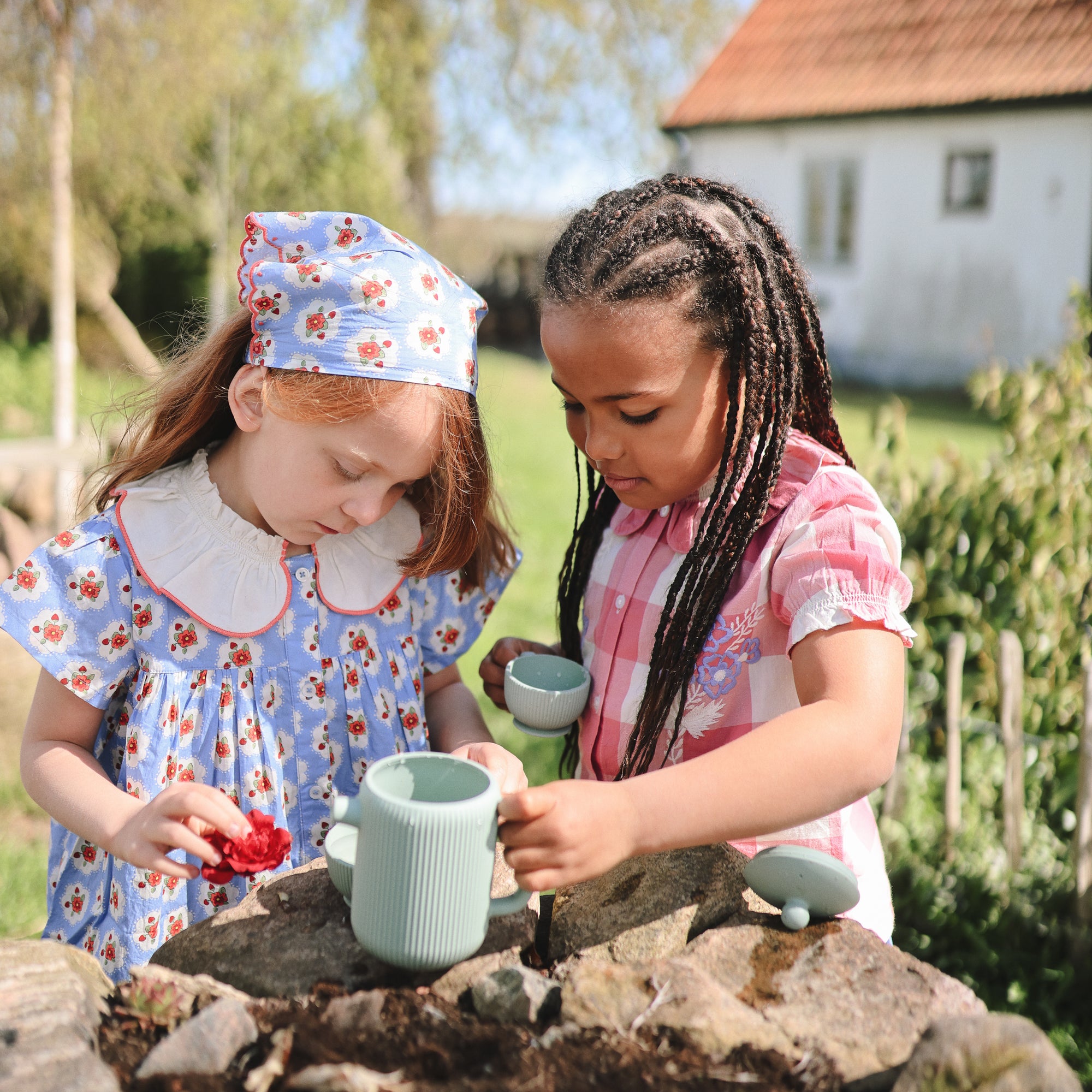 Two young girls host an outdoor tea party with the Mushie Silicone Tea Play Set.