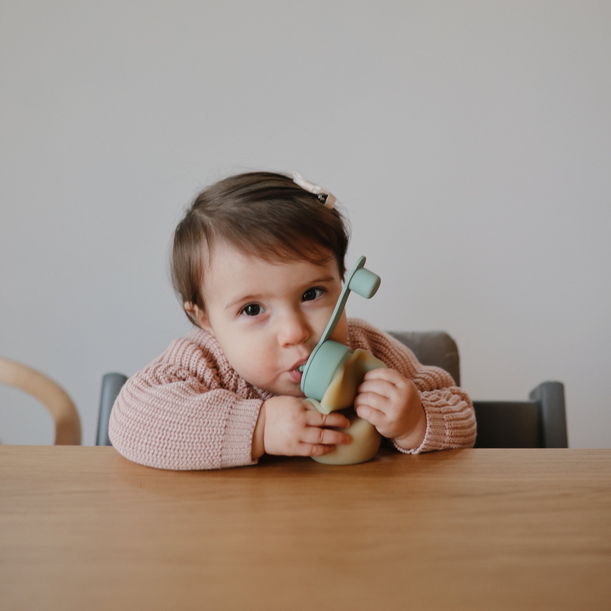 Toddler enjoys mess-free feeding at the table with the mushie Silicone Puree Pouch.