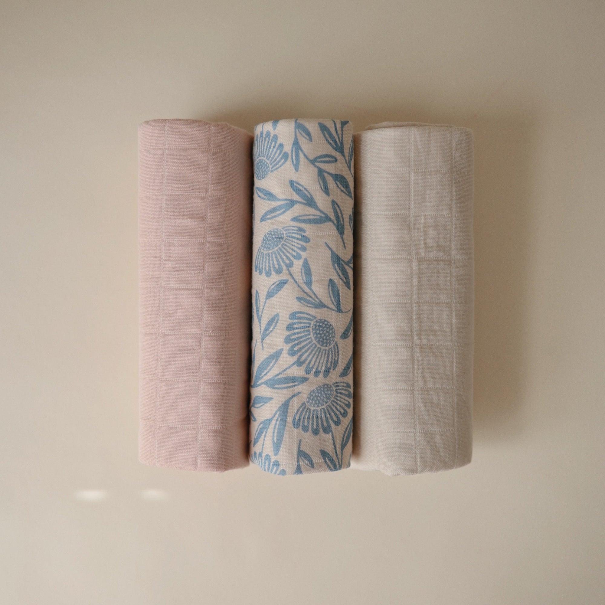 Three Mushie Changing Pad Liners: pink, floral blue/white, beige, made from organic cotton.