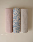 Three Mushie Changing Pad Liners: pink, floral blue/white, beige, made from organic cotton.