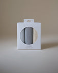 Three Mushie Changing Pad Liners, folded in a white box with a round window on plain background.