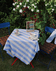 Long sleeve bib by mushie on a table with abacus and bowls near flowering bushes.