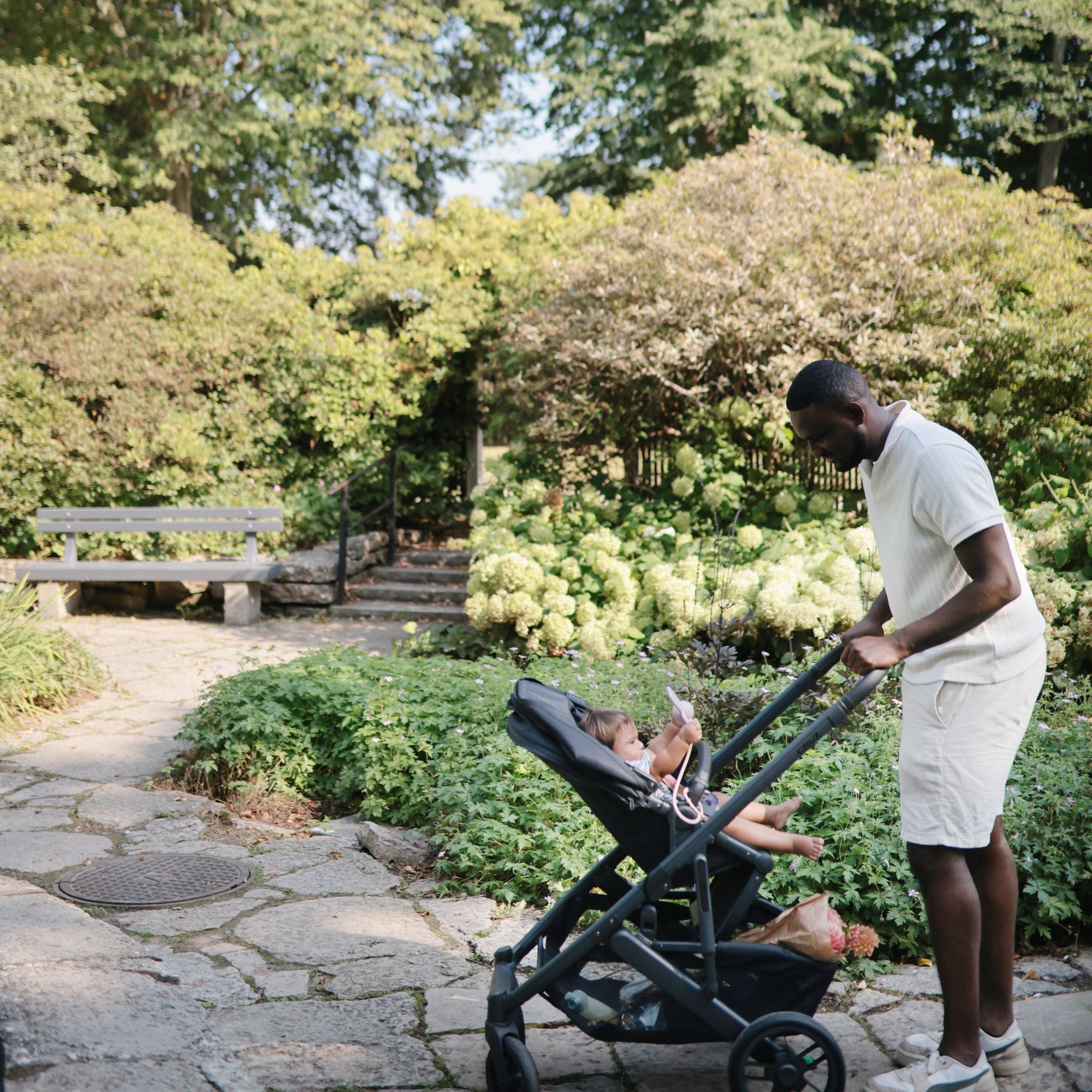 Man pushes stroller with baby and mushie Adjustable Silicone Strap 2-Pack for pacifiers.