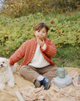 A child and white dog sit on a blanket with a mushie Square Dinnerware Bowls set.