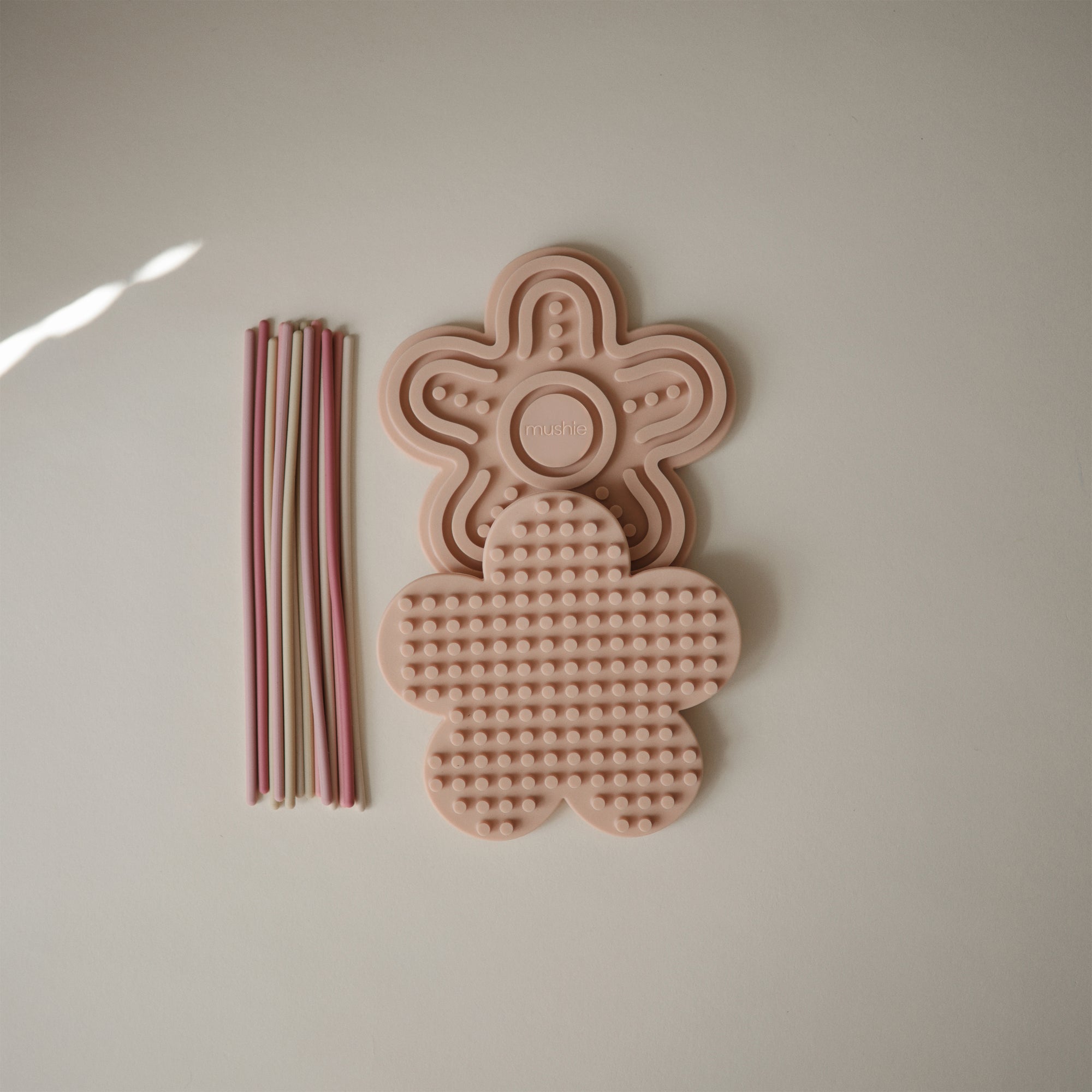 Two mushie Silicone Sensory Toys next to eight pastel straws.