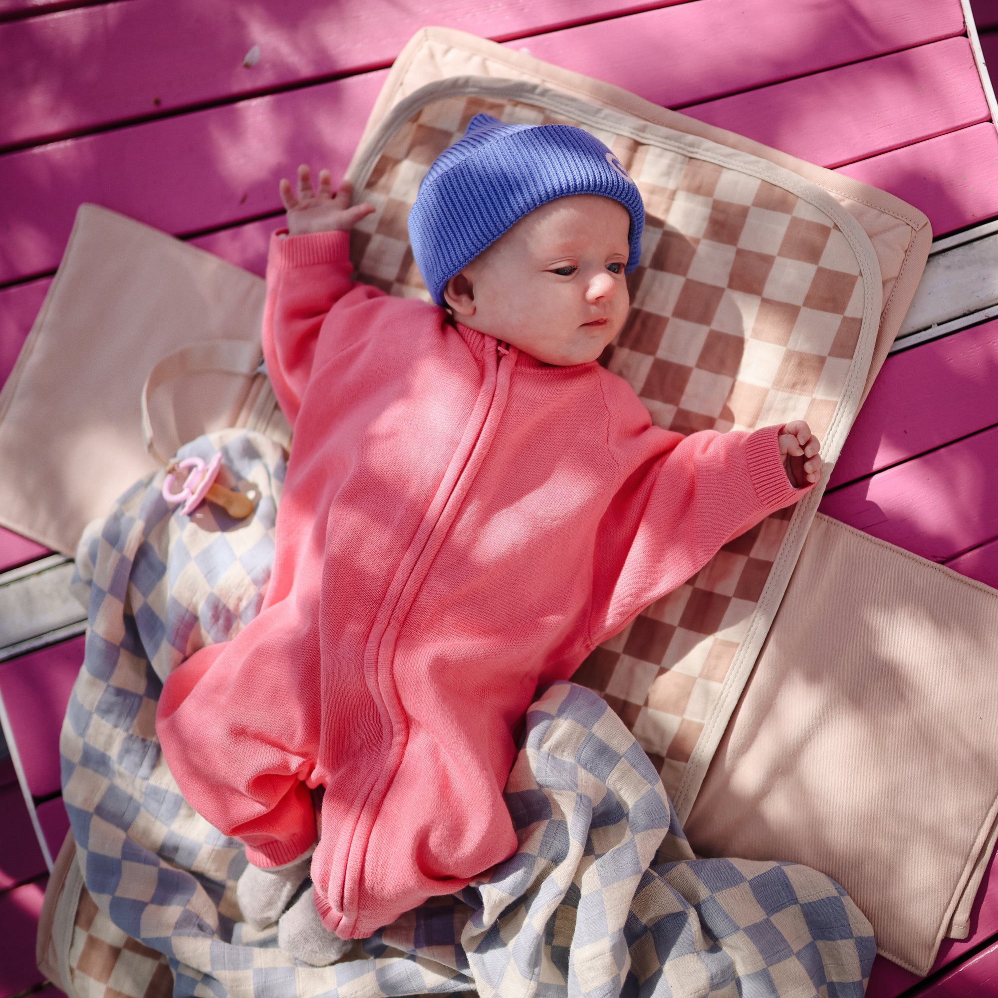 Baby on a mat with the mushie Organic Cotton Muslin Swaddle Blanket.