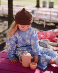 Young child enjoys pretend play with Mushie Silicone Tea Play Set on a pink bench.