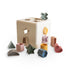 The mushie Shape Sorting Box, in cream, features geometric slots and colorful matching plastic shapes—star, heart, circle, and square—scattered around it to promote hands-on learning and fine motor skills.