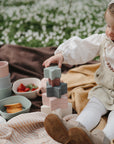 Toddler stacking mushie Nesting Stars Toy on a picnic blanket, building fine motor skills.