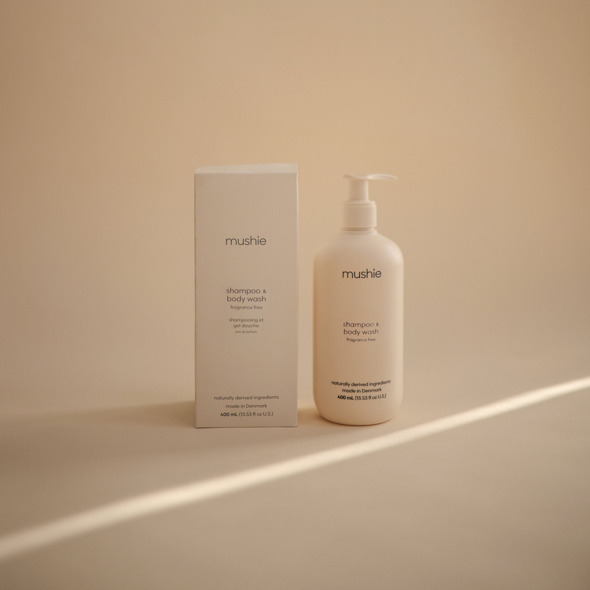 Mushie Baby Shampoo &amp; Body Wash for delicate skin in beige bottle and box on neutral background.