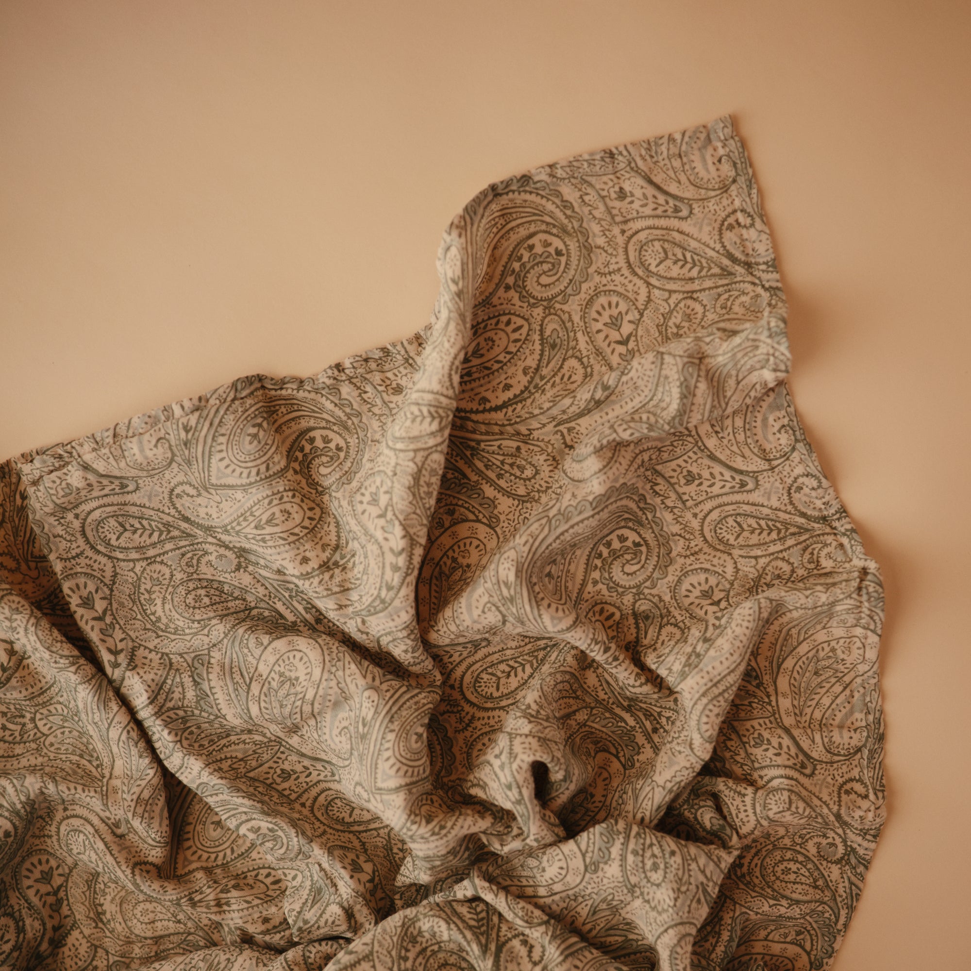 Lifestyle image of Organic Cotton Swaddle in Green Paisley