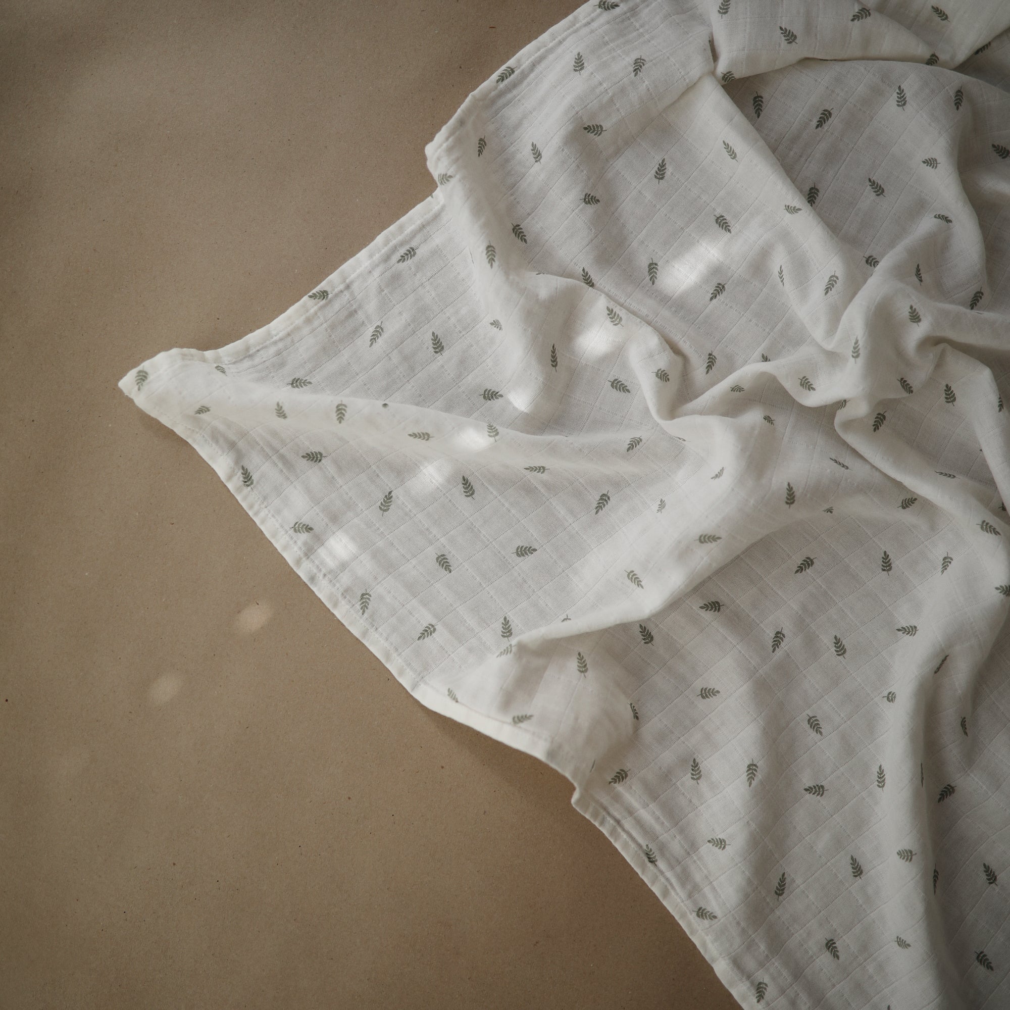 Lifestyle image of Organic Cotton Swaddle in Leaves