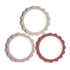 The Mushie Flower Teether Bracelet set features three round, scalloped-edge silicone teethers in beige, light pink, and rose red with a smooth matte finish. Safe and non-toxic, they’re ideal for soothing babies' gums and can be arranged in a triangle.