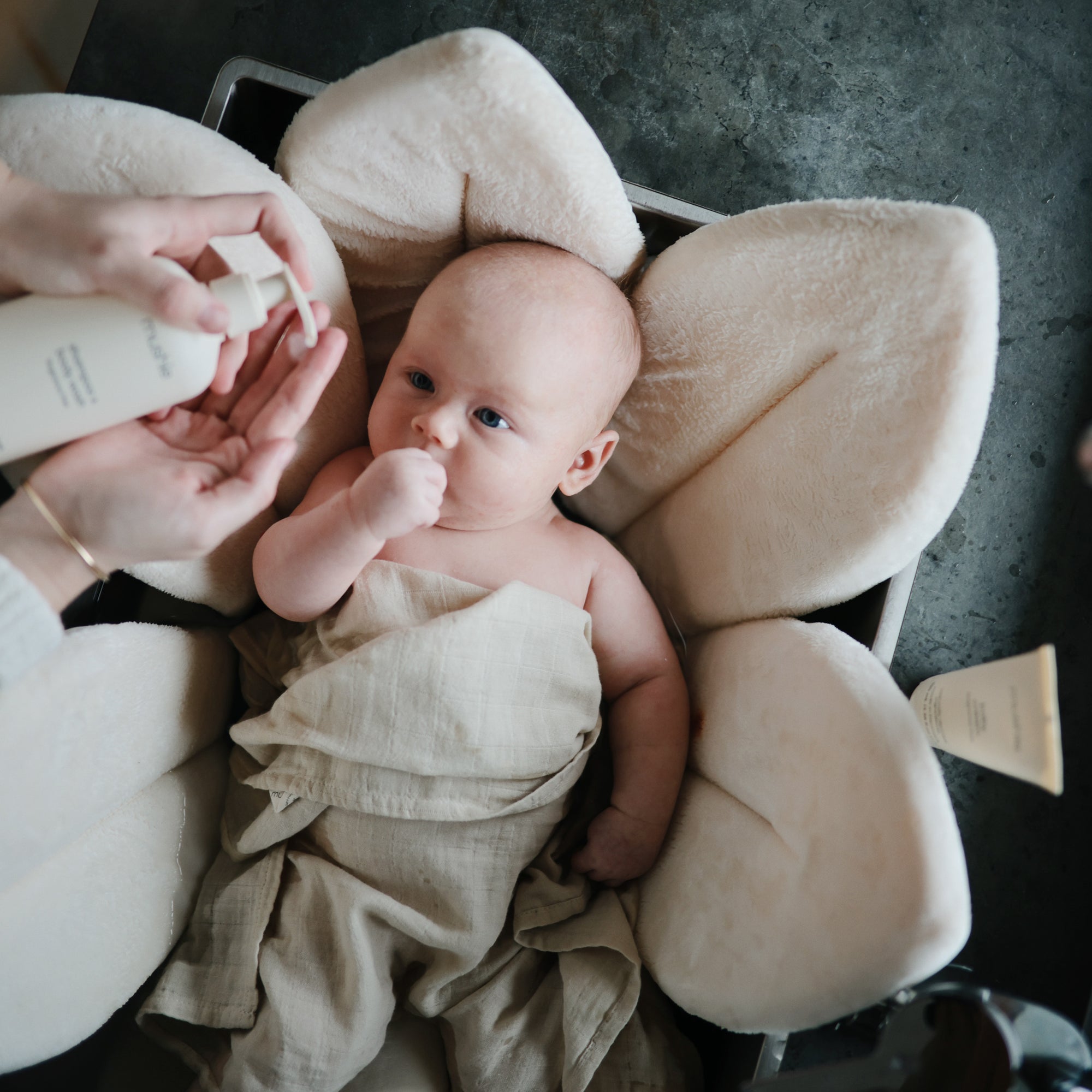 Lifestyle image of a baby swaddled in organic cotton swaddle in Fog