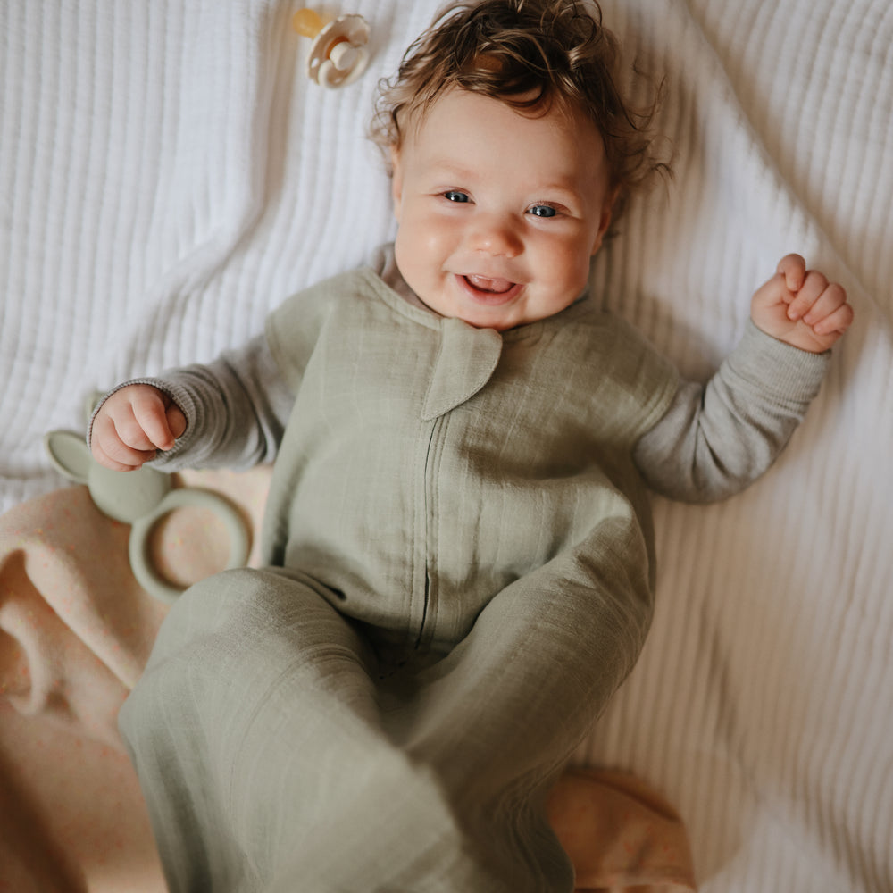 Lifestyle picture of a Mushie Sleep Bag in Sage on a baby.
