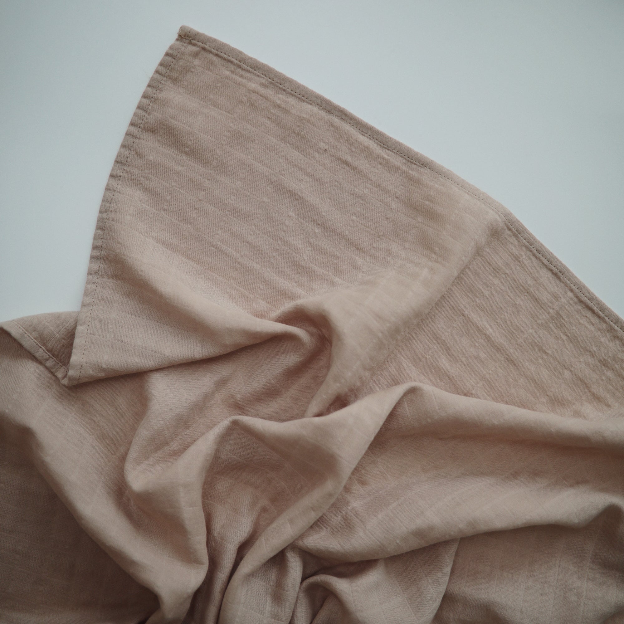 Lifestyle image of Organic Cotton Swaddle in Pale Taupe