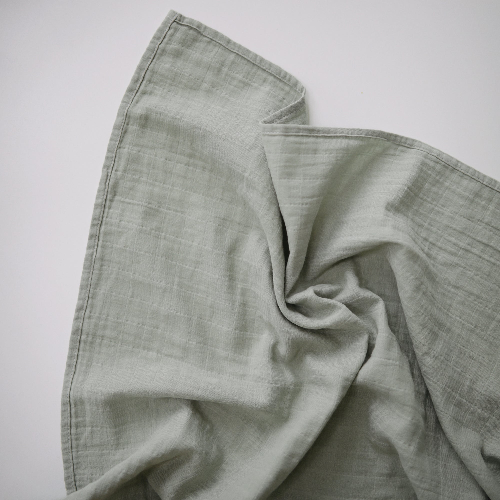 Lifestyle image of Organic Cotton Swaddle in Sage