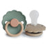 The FRIGG Daisy Silicone Pacifier 2-Pack features two daisy-shaped pacifiers in Willow and Croissant hues, displayed upright and on their side.