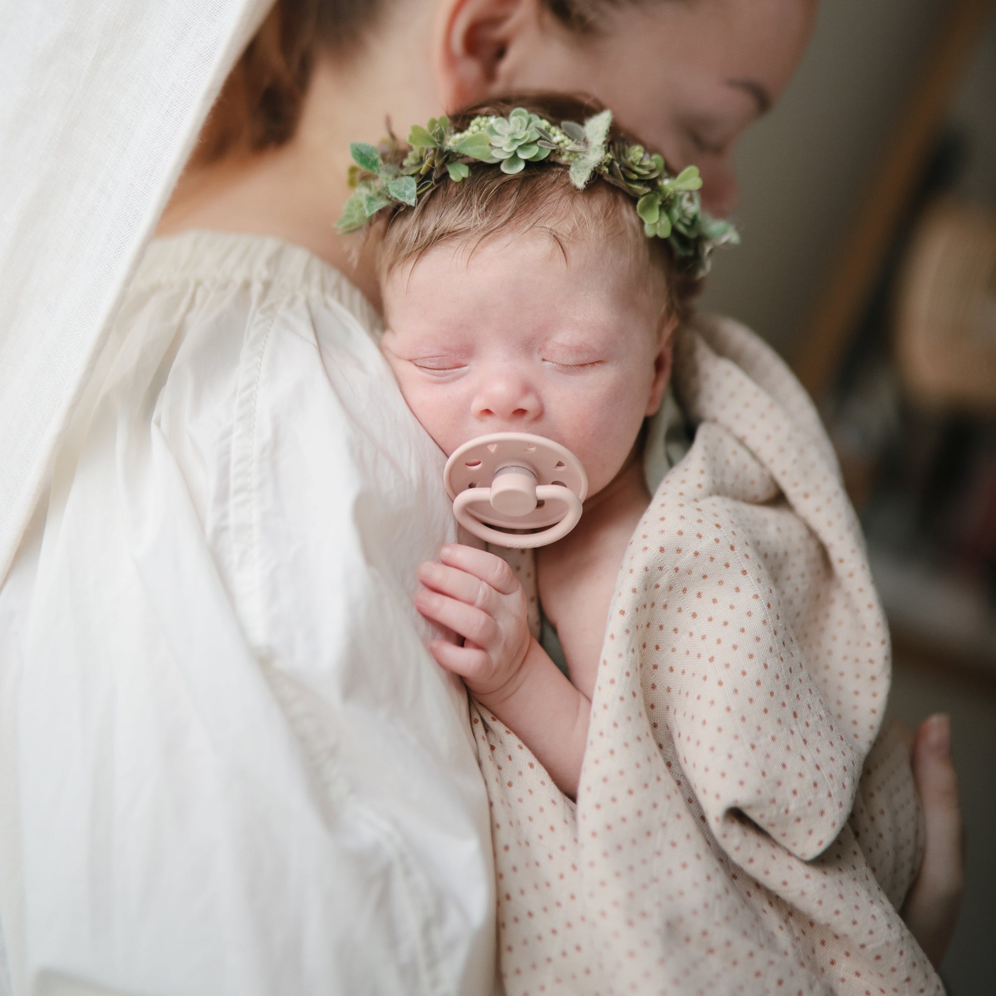 Lifestyle image of a baby swaddled in organic cotton swaddle in Caramel Polka Dot