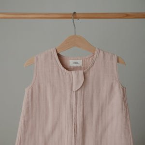Lifestyle image of a Mushie Sleep Bag in Blush on a hanger.
