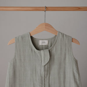Lifestyle image of a Mushie Sleep Bag in Sage on a hanger.