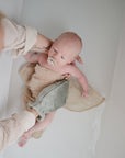 Lifestyle image of a mom using a bath mitt to clean a baby in a shallow tub.