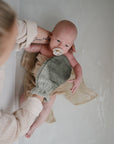 Lifestyle image of a bath mitt cleaning a baby.