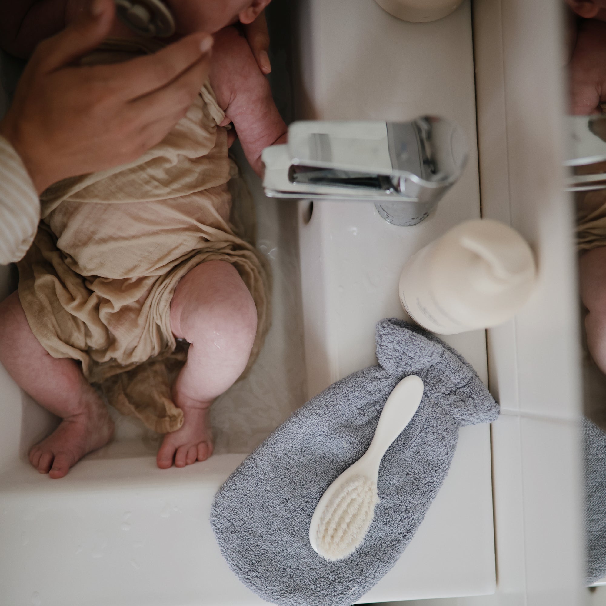 Lifestyle image of a bath mitt resting next to a baby.