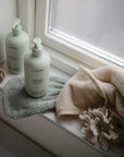 Lifestyle image of a bath mitt and Green Lemon Baby Skincare